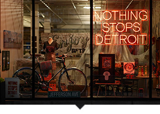 Neon sign in window of store that reads Nothing Stops Detroit